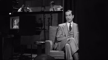 Movie still from “Good Night, and Good Luck.” (2005), directed by George Clooney – A man in a suit and tie sitting in a chair; Medium shot, Over the shoulder angle