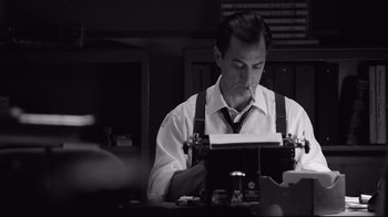 Movie still from “Good Night, and Good Luck.” (2005), directed by George Clooney – A man sitting at a table with a typewriter; Medium shot, Low angle