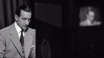 Movie still from “Good Night, and Good Luck.” (2005), directed by George Clooney – A man wearing a suit and tie in front of a bus; Close Up shot, Over the shoulder angle