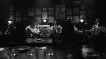 Movie still from “Good Night, and Good Luck.” (2005), directed by George Clooney – A group of men sitting at a table in a room; Wide shot, Over the shoulder angle