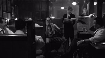 Movie still from “Good Night, and Good Luck.” (2005), directed by George Clooney – Two men in suits and hats are sitting in a room; Wide shot, Over the shoulder angle
