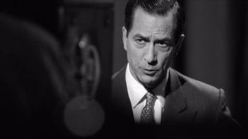 Movie still from “Good Night, and Good Luck.” (2005), directed by George Clooney – Black and white photograph of a man wearing a suit and tie; Close Up shot, Over the shoulder angle