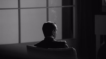 Movie still from “Good Night, and Good Luck.” (2005), directed by George Clooney – A man in a suit sitting in front of a window; Medium shot, Over the shoulder angle