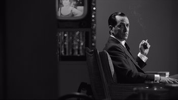 Movie still from “Good Night, and Good Luck.” (2005), directed by George Clooney – A black and white photo of a man sitting in a chair; Medium shot, Over the shoulder angle