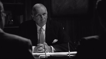 Movie still from “Good Night, and Good Luck.” (2005), directed by George Clooney – An older man sitting at a table with papers; Medium shot, Over the shoulder angle