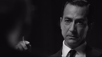 Movie still from “Good Night, and Good Luck.” (2005), directed by George Clooney – Black and white photograph of a man smoking a cigarette; Close Up shot, Low angle