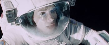 Movie still from “Gravity” (2013), directed by Alfonso Cuarón – A person in a spacesuit looking into a mirror; Close Up shot, Overhead angle