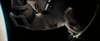 Movie still from “Gravity” (2013), directed by Alfonso Cuarón – An image of an astronaut in the dark; Close Up shot, Overhead angle