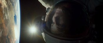 Movie still from “Gravity” (2013), directed by Alfonso Cuarón – A person in a space suit looking into a mirror; Close Up shot, Overhead angle