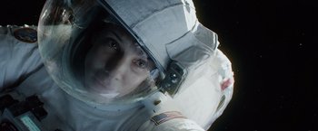 Movie still from “Gravity” (2013), directed by Alfonso Cuarón – A man in a spacesuit looking into the camera; Close Up shot, Overhead angle