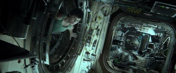 Movie still from “Gravity” (2013), directed by Alfonso Cuarón – A woman is looking out of a space station window; Medium shot, Overhead angle