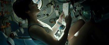 Movie still from “Gravity” (2013), directed by Alfonso Cuarón – A woman is holding papers in her hands; Medium shot, Overhead angle