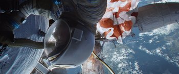 Movie still from “Gravity” (2013), directed by Alfonso Cuarón – A person in a space suit hanging from the side of a building; Wide shot, Overhead angle