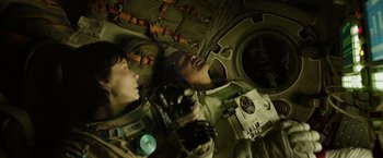 Movie still from “Gravity” (2013), directed by Alfonso Cuarón – Two people in space suits looking up into a space station; Medium shot, Overhead angle