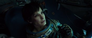 Movie still from “Gravity” (2013), directed by Alfonso Cuarón – A woman in a space suit looking into the distance; Close Up shot, Overhead angle