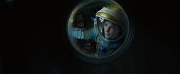 Movie still from “Gravity” (2013), directed by Alfonso Cuarón – A man in a spacesuit looking into a mirror; Medium shot, Overhead angle