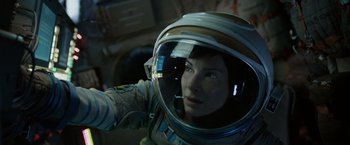 Movie still from “Gravity” (2013), directed by Alfonso Cuarón – A woman in a spacesuit is looking at the camera; Close Up shot, Overhead angle