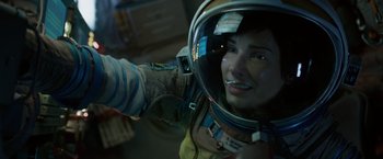Movie still from “Gravity” (2013), directed by Alfonso Cuarón – A woman wearing a space suit and a helmet; Close Up shot, Overhead angle