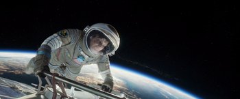 Movie still from “Gravity” (2013), directed by Alfonso Cuarón – A man in a spacesuit and a helmet in front of the earth; Wide shot, Overhead angle