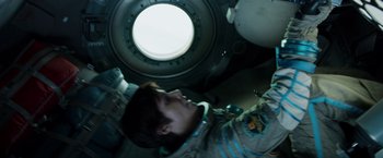 Movie still from “Gravity” (2013), directed by Alfonso Cuarón – A man in a space suit looking up at the ceiling; Medium shot, Overhead angle