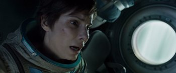 Movie still from “Gravity” (2013), directed by Alfonso Cuarón – A woman with short brown hair wearing a space suit; Close Up shot, Overhead angle