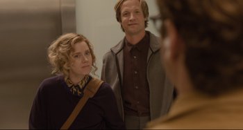 Movie still from “Her” (2013), directed by Spike Jonze – A man and a woman standing next to each other in front of another man; Medium shot, Over the shoulder angle