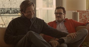 Movie still from “Her” (2013), directed by Spike Jonze – A man sitting next to another man on a couch; Medium shot, Over the shoulder angle