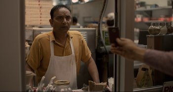 Movie still from “Her” (2013), directed by Spike Jonze – A person taking a picture of a man in an apron in front of a mirror; Close Up shot, Over the shoulder angle