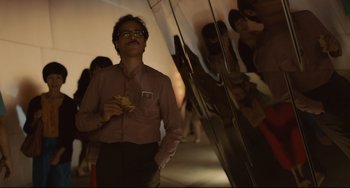Movie still from “Her” (2013), directed by Spike Jonze – A man standing next to a crowd of people in a building; Medium shot, Over the shoulder angle