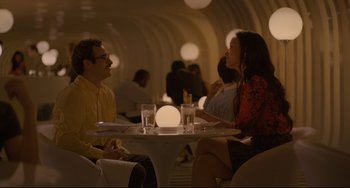Movie still from “Her” (2013), directed by Spike Jonze – A man and a woman are sitting at a table; Wide shot, High angle