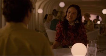 Movie still from “Her” (2013), directed by Spike Jonze – A woman sitting at a table in front of other people; Medium shot, Over the shoulder angle