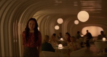 Movie still from “Her” (2013), directed by Spike Jonze – A woman standing in front of a group of people in a room; Medium shot, Over the shoulder angle
