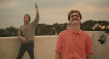 Movie still from “Her” (2013), directed by Spike Jonze – A man with a beard and glasses is holding a cell phone in his hand; Medium shot, Low angle