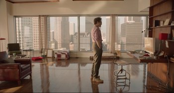 Movie still from “Her” (2013), directed by Spike Jonze – A man standing in a room with a view of a city; Wide shot, Over the shoulder angle