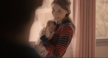 Movie still from “Her” (2013), directed by Spike Jonze – A woman holding a baby in her arms and smiling; Medium shot, Over the shoulder angle
