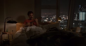 Movie still from “Her” (2013), directed by Spike Jonze – A man sitting in a bed playing a ukulele; Wide shot, High angle