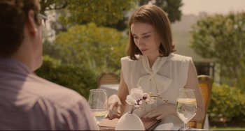 Movie still from “Her” (2013), directed by Spike Jonze – A woman sitting at a table with a vase of flowers; Medium shot, Over the shoulder angle