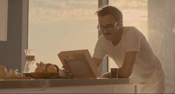 Movie still from “Her” (2013), directed by Spike Jonze – A man is looking at a book on a table; Close Up shot, Low angle