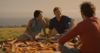 Movie still from “Her” (2013), directed by Spike Jonze – A man and a woman sitting on a blanket in a field; Medium shot, Over the shoulder angle