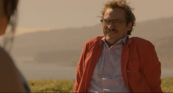 Movie still from “Her” (2013), directed by Spike Jonze – A man in a red jacket is smiling for the camera; Close Up shot, Over the shoulder angle