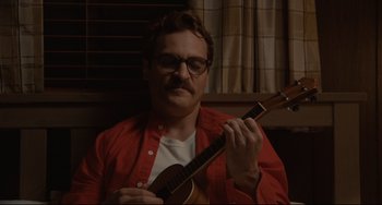 Movie still from “Her” (2013), directed by Spike Jonze – A man in a red shirt is playing a ukulele; Close Up shot, Over the shoulder angle