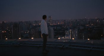 Movie still from “Her” (2013), directed by Spike Jonze – A man standing on a rooftop looking out over a city at night; Wide shot, High angle