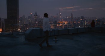 Movie still from “Her” (2013), directed by Spike Jonze – A man standing on a rooftop in front of a city skyline at night; Extreme Wide shot, High angle