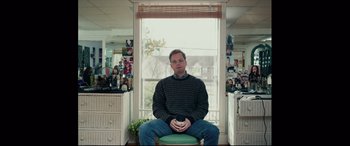 Movie still from “I, Tonya” (2017), directed by Craig Gillespie – A man sitting on a stool in front of a window; Medium shot, Over the shoulder angle