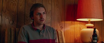 Movie still from “I, Tonya” (2017), directed by Craig Gillespie – A man standing next to a wooden wall in a room; Close Up shot, Low angle
