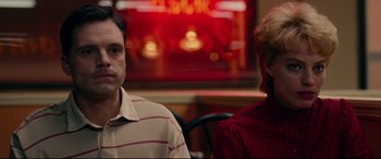 Movie still from “I, Tonya” (2017), directed by Craig Gillespie – A man and a woman sitting at a table in front of a neon sign; Close Up shot, Low angle
