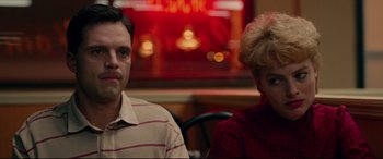 Movie still from “I, Tonya” (2017), directed by Craig Gillespie – A man and a woman sitting at a table in front of a neon sign; Close Up shot, Low angle