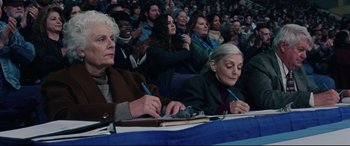 Movie still from “I, Tonya” (2017), directed by Craig Gillespie – A group of people sitting at a table with pens; Medium shot, High angle