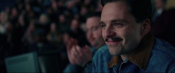 Movie still from “I, Tonya” (2017), directed by Craig Gillespie – A man with a mustache sitting in front of an audience; Close Up shot, Low angle