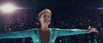 Movie still from “I, Tonya” (2017), directed by Craig Gillespie – A female figure skating skater is smiling and holding her arms out; Close Up shot, Low angle